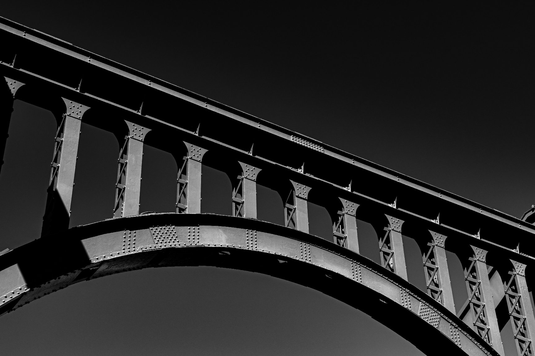 L’arche d’un pont métallique riveté, en noir et blanc